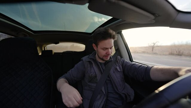 Man driving car and looking at phone at sunny day interior view