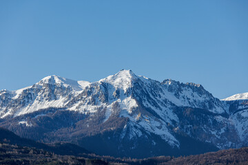 Fototapeta na wymiar A scenic view of majestic snowy mountain with pine forest under a majestic blue sky