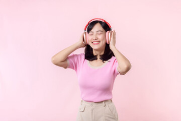 Fototapeta na wymiar Smile pretty model person listen music song and enjoy dance with wireless headphone online audio radio sound. Positive fun exited joyful youth female woman sing on pink isolated background studio
