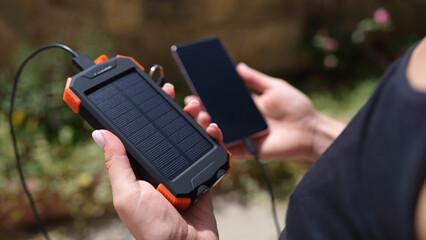 Mobile phone and solar power bank in hands closeup