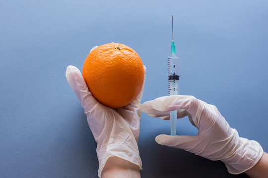 GMO concept. Orange in hands modified by injecting