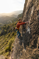 Obraz premium man climbing at sunset in the mountains with the forest in the background, copy space, business, security, trust