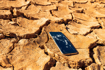 smartphone with a broken screen on the soil during a drought