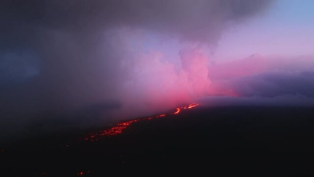 Breathtaking pink scarlet sunset or sunrise clouds above erupting volcano on Hawaiian Big Island, USA tourism. Aerial above beautiful hot red lava river flow under purple clouds at Mauna Loa mountain