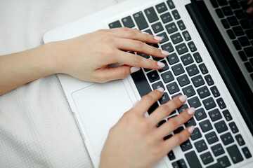 Close up of female hands pressing keys of laptop keypad.