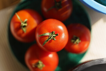 Ripe red tomatoes on a plate shot from above. Pile of fresh vegetables prepared for cooking