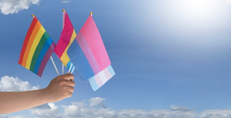 Fototapeta premium Rainbow flag and LGBTQ+ flags holding in hand isolated on white background, copy space, clipping paths, concept for lgbtq+ celebrations in pride month, june, 2023.
