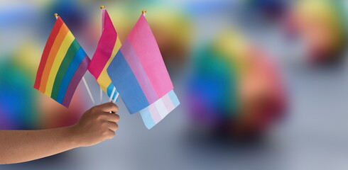 Rainbow flag and LGBTQ+ flags holding in hand isolated on white background, copy space, clipping paths, concept for lgbtq+ celebrations in pride month, june, 2023.