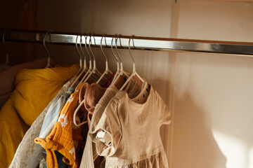 Fototapeta na wymiar Children's clothes, girls' dresses hang on hangers in an open closet, dressing room
