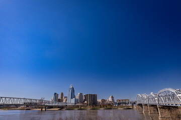 The Cincinnati cityscape, viewed from the opposite shore of the Ohio River, displays several bridges spanning the waterway.