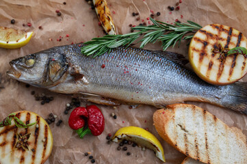 Appetizing sibas fish with greens and vegetables. On a wooden background.