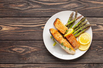 Baked salmon with asparagus and lemon on gray wooden background. Mediterranean diet concept. Copy space