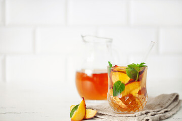 Fruit iced tea with peaches and apples in a glass on the table. Summer drink concept
