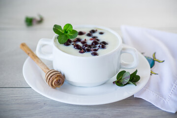 Cooked milk semolina porridge with berries and honey in a plate.