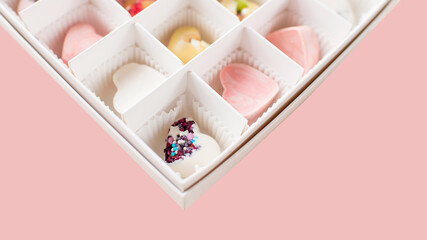 set of different sweets, candies, in boxes on a plain soft pink background.