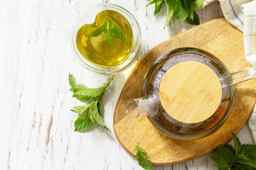 Cup and teapot of fresh natural herbal tea with fresh mint leaves on rustic wooden table. Organic aromatherapy relaxation medical healthy drink. View from above. Copy space.