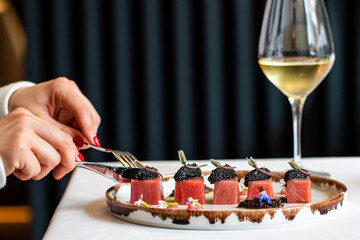 Side view of female hands with bluefin tuna dish in restaurant