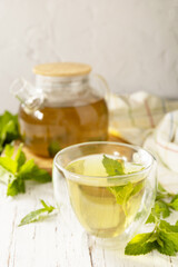Cup and teapot of fresh natural herbal tea with fresh mint leaves on rustic wooden table. Organic aromatherapy relaxation medical healthy drink. Copy space.