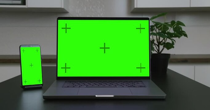 Close-up of laptop and smartphone with empty green blank screen mockup.