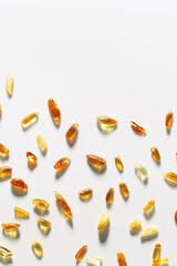 Natural Amber texture background, yellow orange colored stones with shadow on white. Natural gemstone mineral material for jewelry. Transparent pieces gem Amber scattered on white, top view
