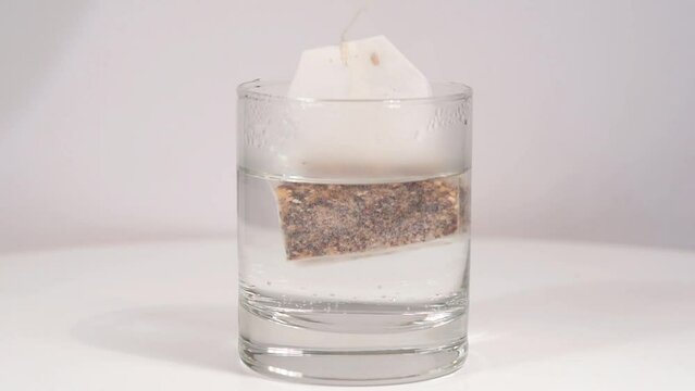 una bustina di the ai frutti in infusione in un bicchiere d'acqua, bustina di the a mollo