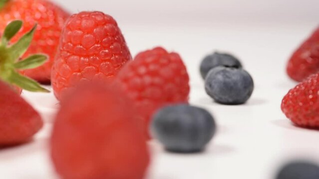 un bel mix di frutti rossi per la dieta, lamponi fragole  mirtilli su sfondo bianco.