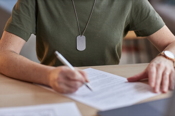 Close up of unrecognizable military woman signing contract in office, copy space