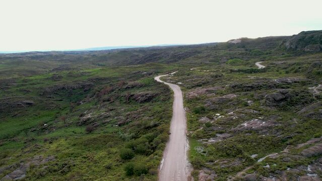 Camino, carretera, de ripio en pradera monta&ntilde;osa un d&iacute;a soleado, visto desde un dron. C&oacute;rdoba, Argentina, Latinoam&eacute;rica