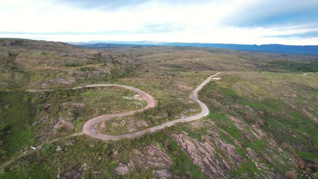 Camino, carretera, de ripio en pradera monta&ntilde;osa un d&iacute;a soleado, visto desde un dron. C&oacute;rdoba, Argentina, Latinoam&eacute;rica