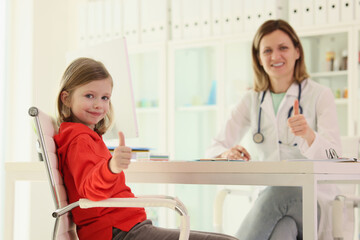 Little girl and doctor shows thumbs up at appointment