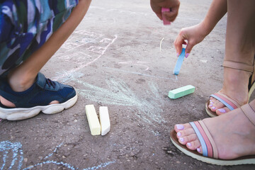 Children draw with chalk on the road. Children's creativity on the street.