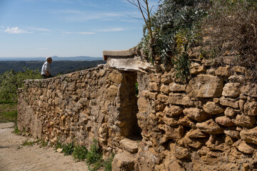 retired man sitting on an old stone wall in the street of a small village in huesca, a micro...