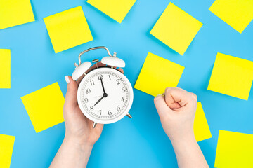 White alarm clock and yellow paper reminder,coming soon. Blank yellow sticky notes on a blue...