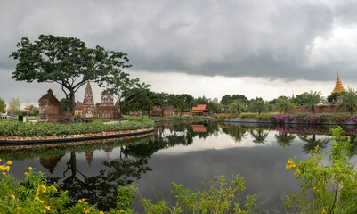 Obraz premium Panoramic photo of the architectural park of Oriental culture. Religious buildings of Thai history: palace and temple complexes. The exhibits are surrounded by ponds, tropical greenery and flowers