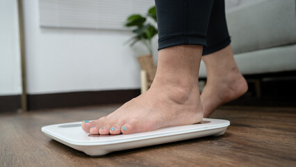 Fat diet and scale feet standing on electronic scales for weight control. Measurement instrument in...