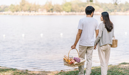 Asian couple walking in garden with picnic basket. in love couple is enjoying picnic time in park outdoors