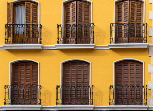 Exterior de una casa con fachada amarilla y ventanas con persianas de madera de estilo mediterr&aacute;neo mallorqu&iacute;n.