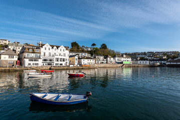 Fototapeta na wymiar View of the pretty historic Cornish fishing village of Polperro with the harbour, fishing boats and fishermans cottages in sunshine
