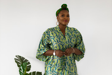 Portrait of cheerful african american woman with headscarf turban against white wall. Happy smiling...