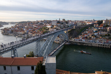Obraz premium Imagen desde lo alto del puente de Don Luis I en Oporto con la ciudad al fondo bajo un cielo nublado de primavera.