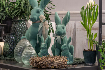 A wicker basket made of birch branches, a large family of bunnies in mint color, large glass eggs.