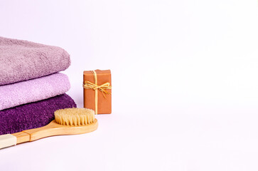 Colored terry towels, a wooden brush for dry massage, soap on a white background.