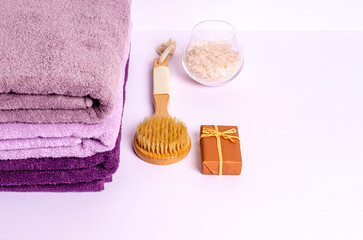 Stack of colored bath towels with body care products on a white background.