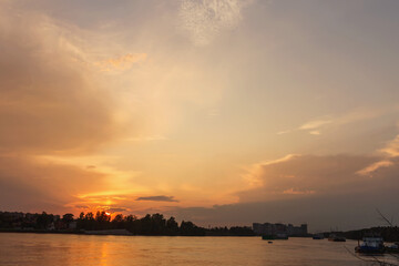 a sky with golden clouds beautifully illuminated by the sun over a wide river - 585909594