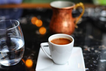 Espresso coffee in a white cup. Glass of water.
