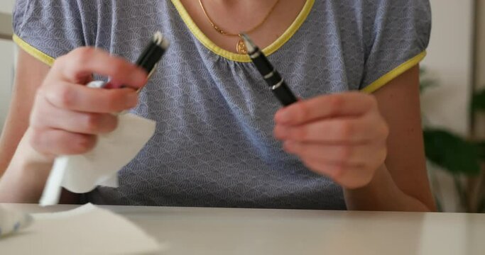 Front view of woman cleaning fountain pen after filling it with blue ink pen