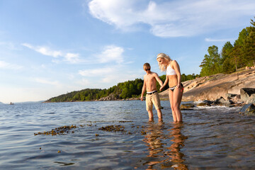 Man helping beautiful woman and holding hands when standing in the water