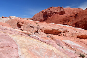 Fototapeta premium Amazing colors and massive formations around the Fire Wave rock in Valley of Fire State Park, Nevada, USA. Pink and red pastel colors of the sandstone and blue sky in the background