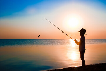 A Happy child fisherman fishing by the sea on nature silhouette travel