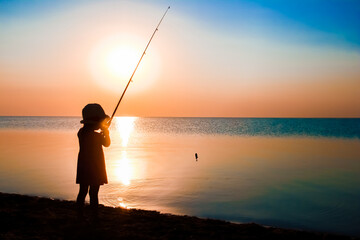 A Happy child fisherman fishing by the sea on nature silhouette travel